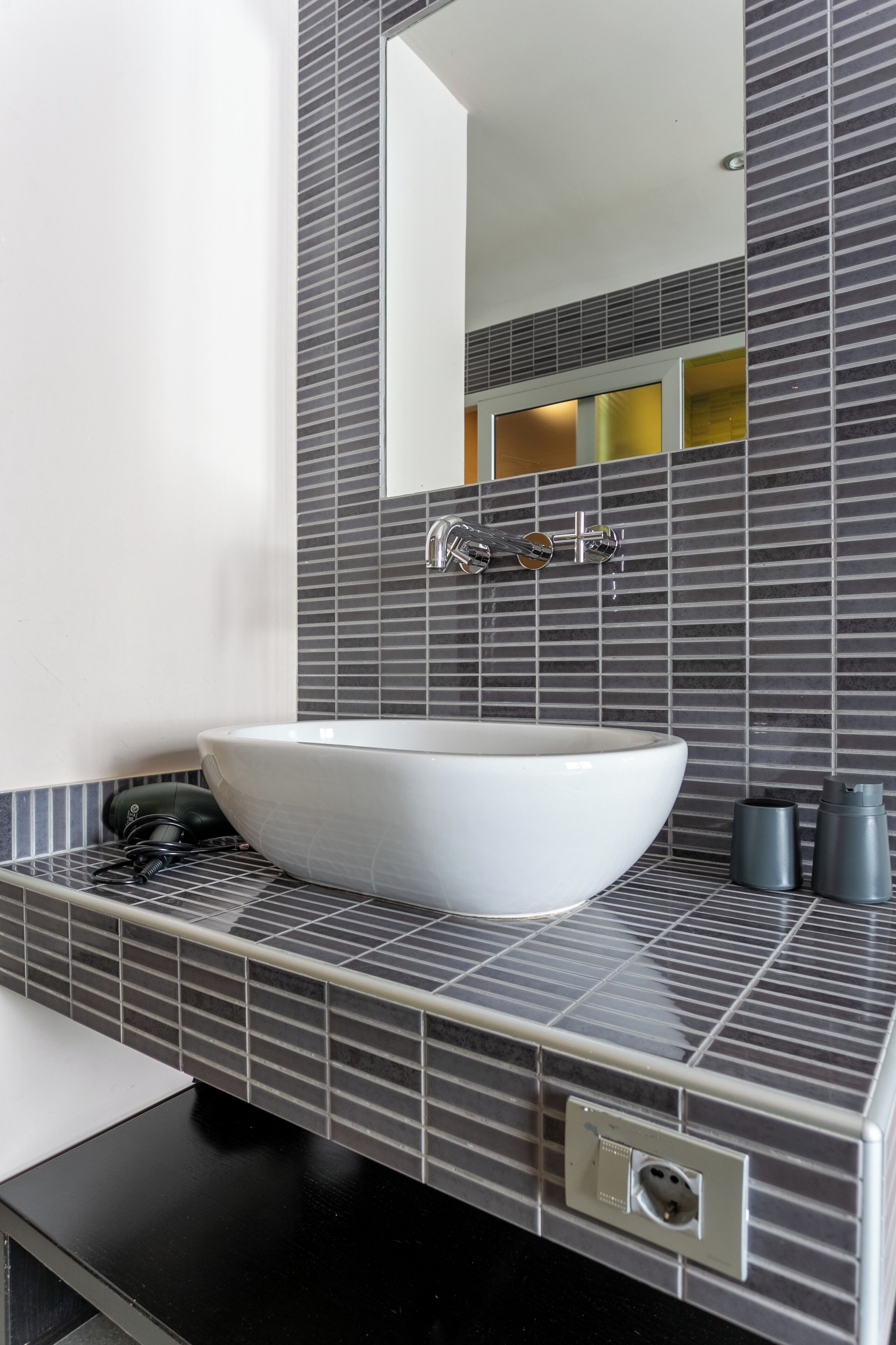 A modern bathroom with a large white sink, a mirror, and a tiled backsplash.