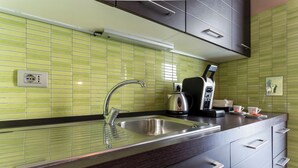 Una cucina moderna con lavandino in acciaio inossidabile, bollitore e macchina del caffè.