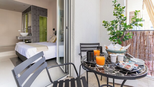 Un balcone con un letto, un tavolo per la colazione e accessori per la colazione.