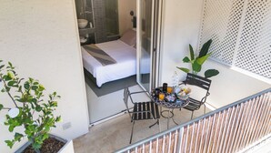 Un balcone con un letto, un tavolino con bevande e una pianta in vaso.