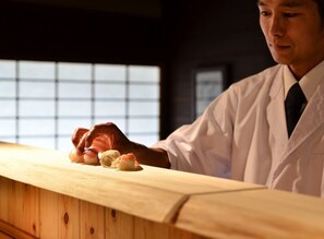 A person in a white lab coat handling objects on a wooden counter.