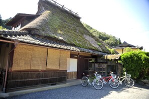 A traditional Japanese building with a thatched roof and wooden walls. There are bicycles parked in front.