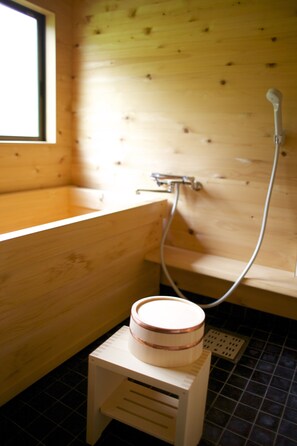 A wooden bathroom with a bathtub, a shower, and a small heater on a stool.