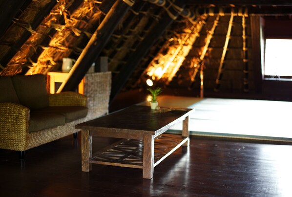 A cozy room with a wooden coffee table, wicker sofa, and a small plant. - Miyama Futon & Breakfast Thatched Cottages (Nantan)