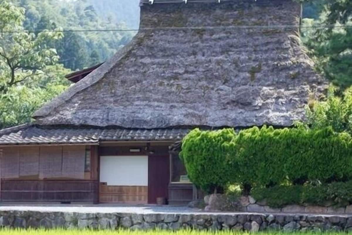 A traditional Japanese building with a sloped roof, wooden structure, and a small garden area.