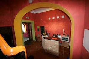 A room with a red wall, a stone counter, and a yellow archway. - El hostel (Warsaw)
