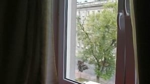 A room with a large window, a red floor, and a curtain. - El hostel (Warsaw)