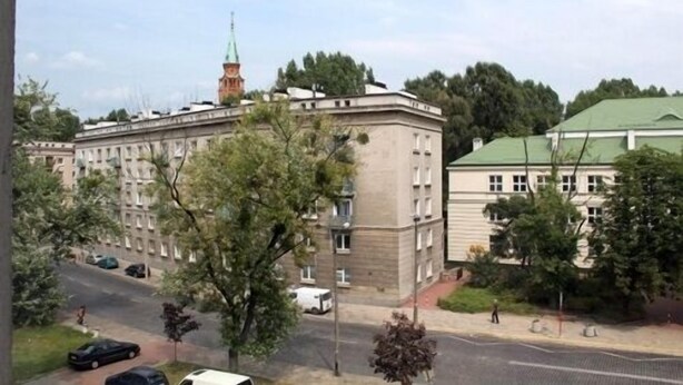 A large building with a green roof, surrounded by trees and parked cars. - El hostel (Warsaw)