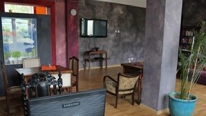 A living room with a flat-screen TV, wooden furniture, a potted plant, and a painting on the wall. - El hostel (Warsaw)