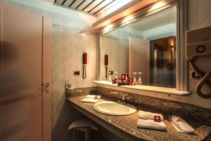 Un baño moderno con encimera de granito, un lavabo, un espejo grande y un perchero para toallas.