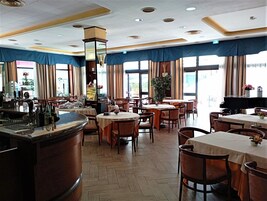 Un restaurante con varias mesas y sillas, una zona de bar y un piano.