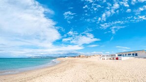 Una playa con un edificio de fachada blanca y techo azul.