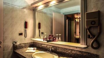 A modern bathroom with a granite countertop, a sink, a large mirror, a handheld showerhead, and a telephone.