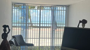 Une pièce dotée d’une grande fenêtre, d’un bureau avec un ordinateur, d’une chaise et d’un objet décoratif.