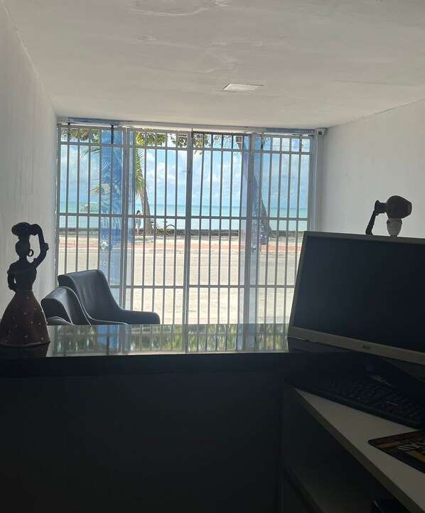 A room with a large window, a desk with a computer, a chair, and a decorative item.