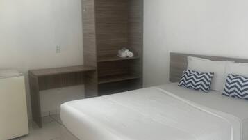 Quarto com cama, guarda-roupa, escrivaninha e ventoinha de teto.