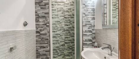 A bathroom with a shower, two sinks, and a toilet.