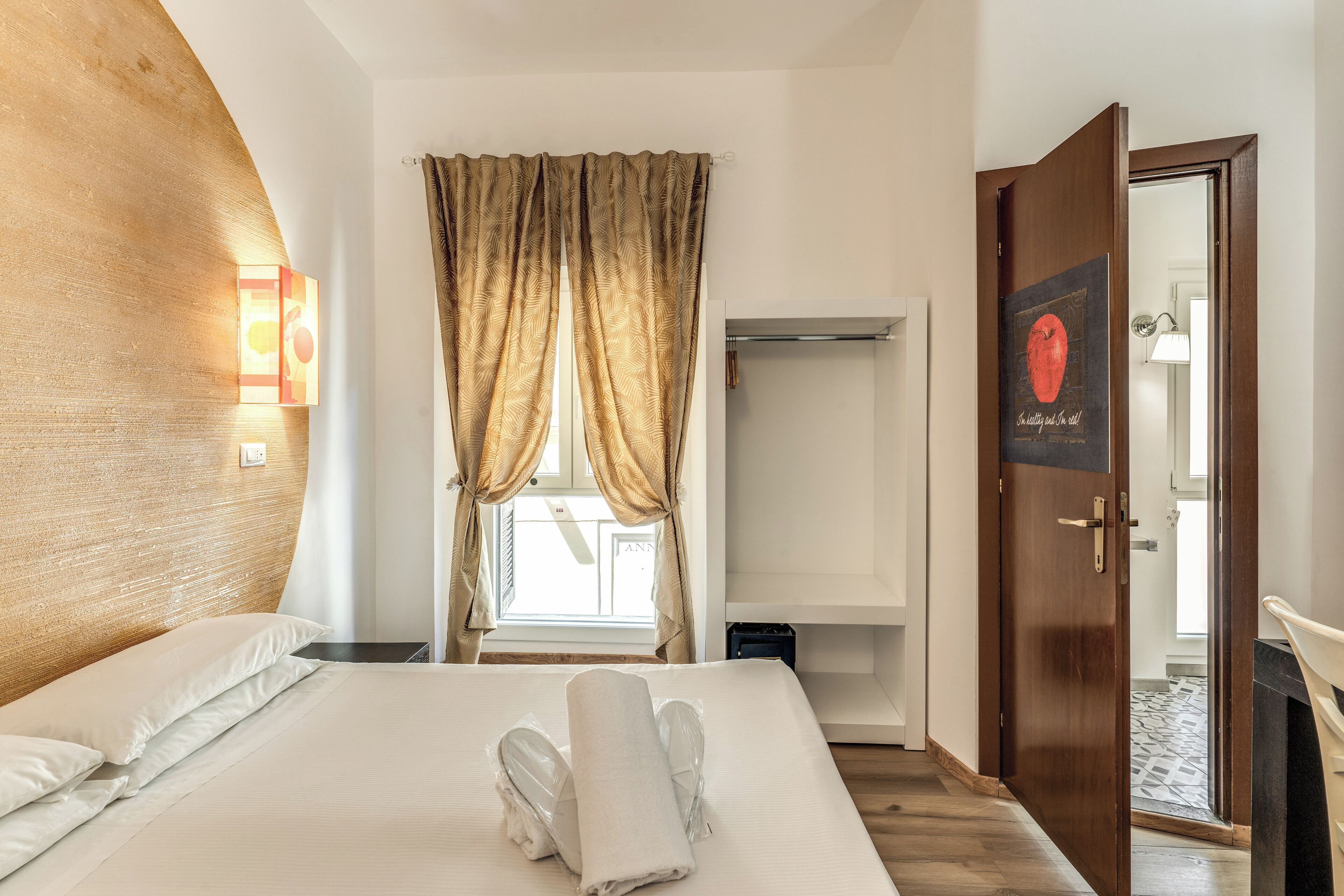 Una habitación de hotel con una cama, un armario y una puerta que da a otra habitación.