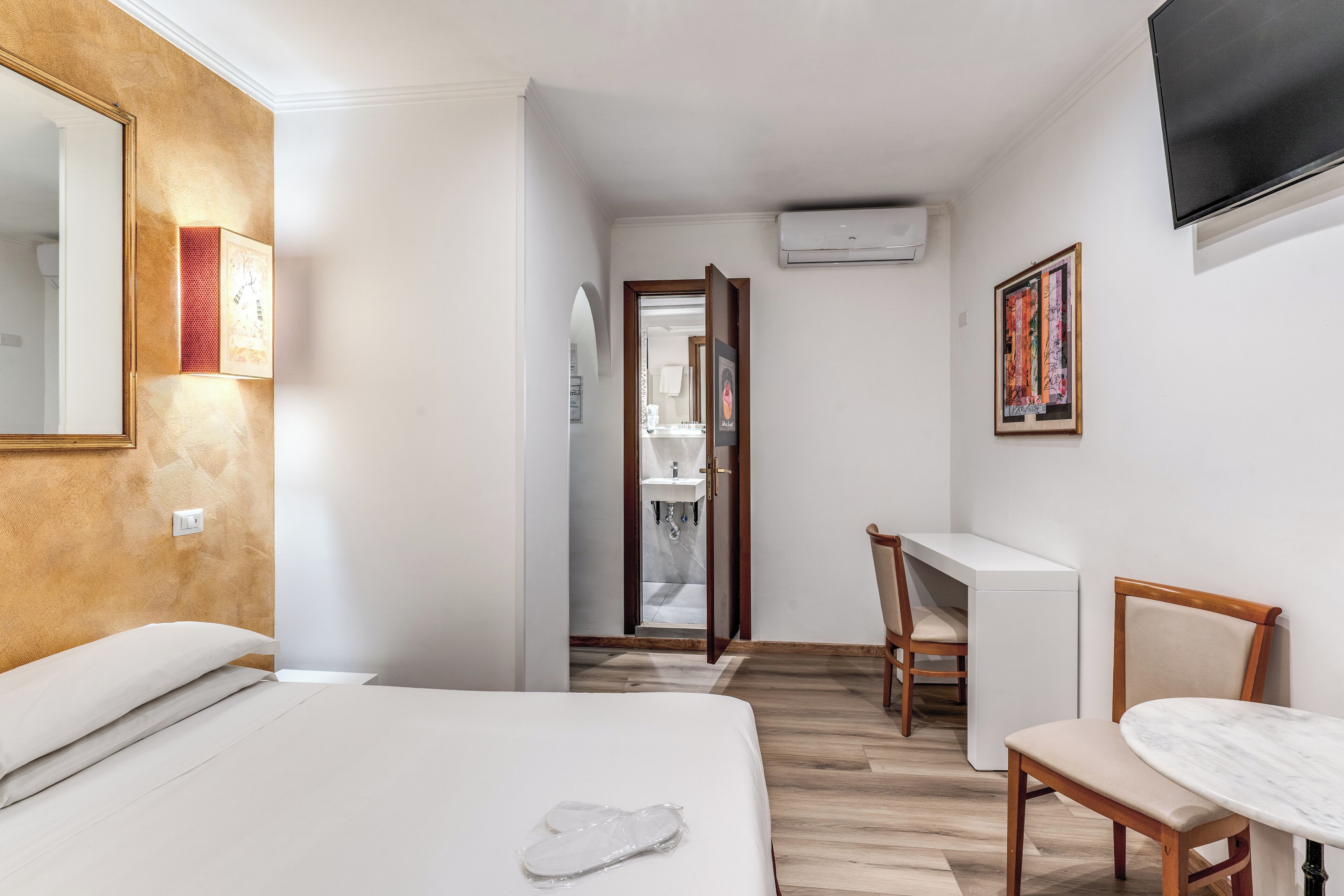 A hotel room with a bed, a desk, a chair, and a TV.