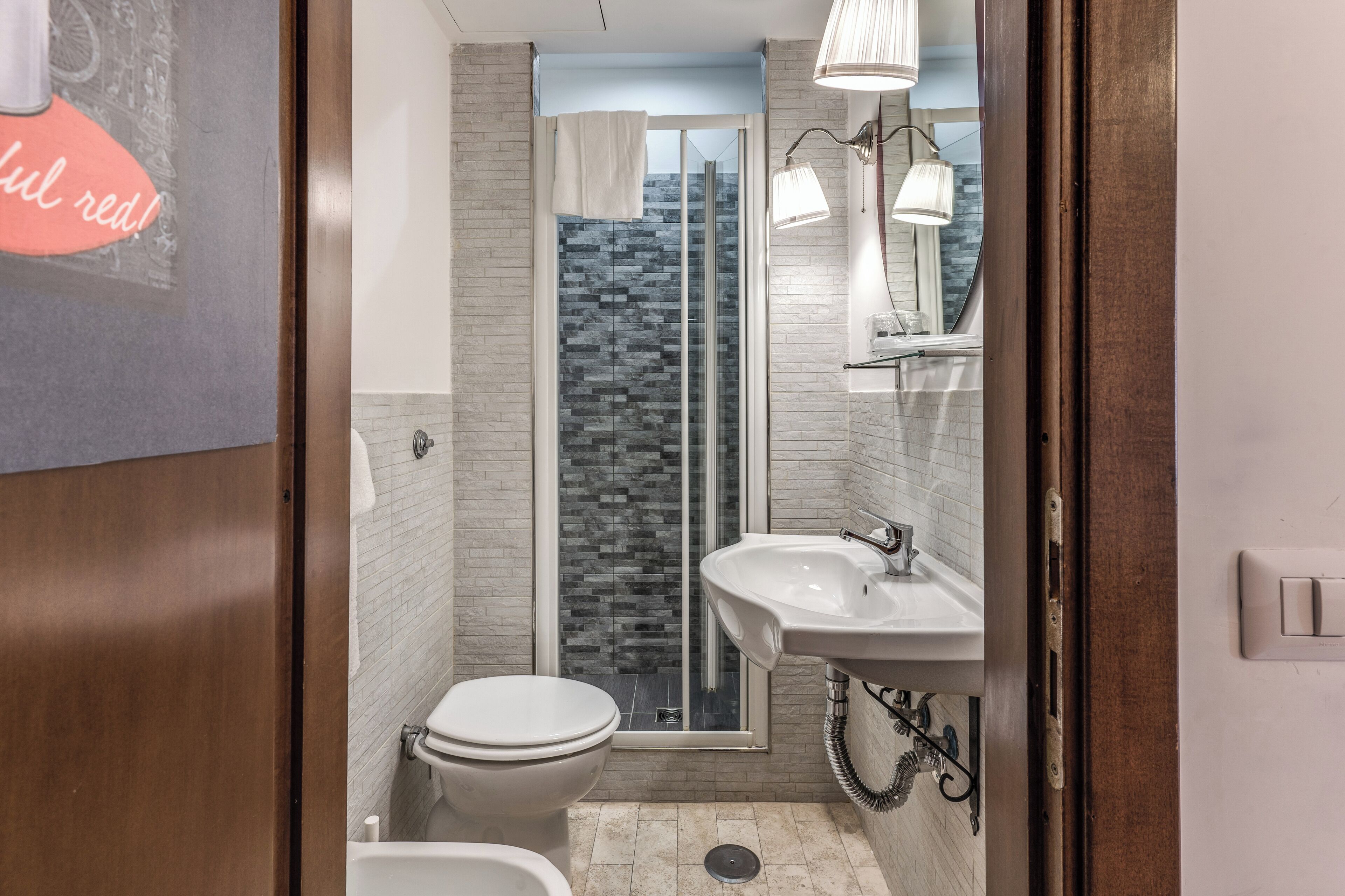 A modern bathroom with a glass shower, a white sink, and a toilet.