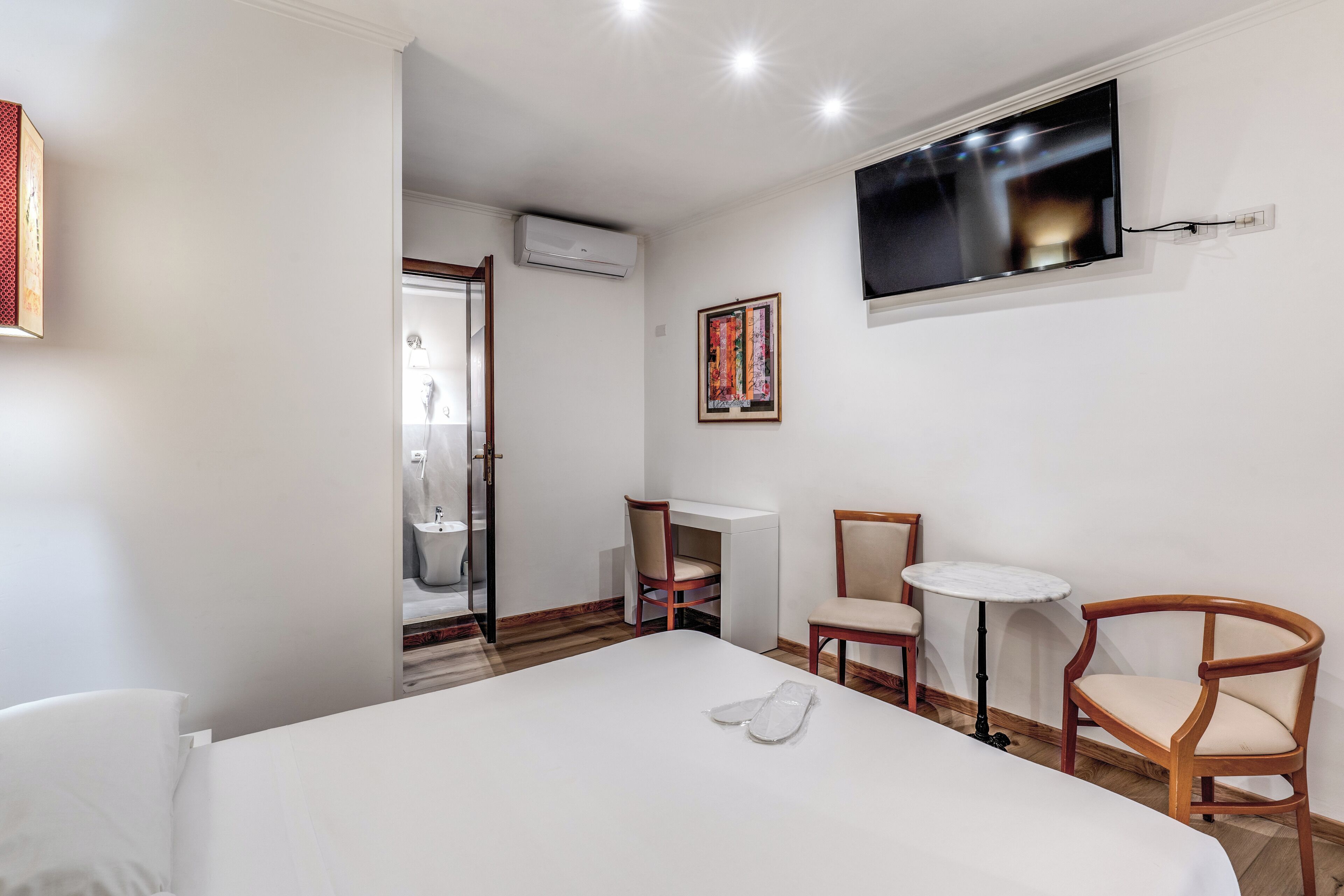 Une chambre d’hôtel équipée d’un lit, d’un bureau, de deux chaises, d’une télévision et d’un appareil de climatisation.