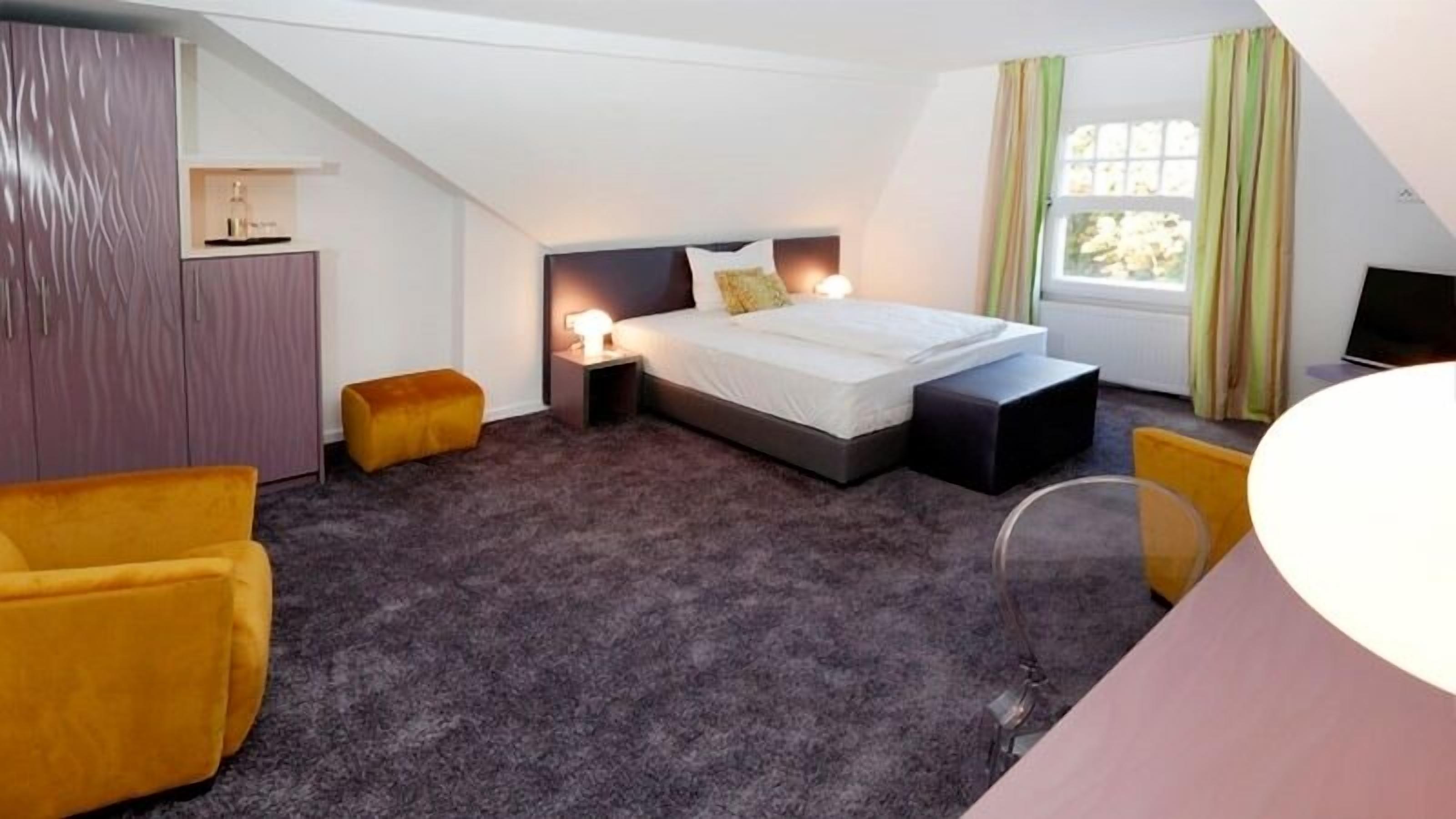 Una camera d'albergo moderna con un letto, comodini, una scrivania e una sedia.