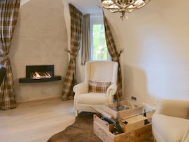 Un salón acogedor con chimenea, un sillón cómodo y una mesa de centro de cristal.