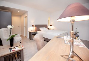 A hotel room with a bed, bedside tables, a desk, a chair, a lamp, and a vase with flowers. - Hotel Park Villa (Wuppertal)