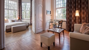 Een ruime kamer met een bed, een bank, een salontafel en een raam met gordijnen.