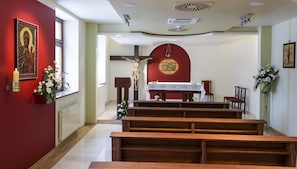 L’intérieur d’une église avec des bancs en bois, un crucifix et des tableaux religieux.