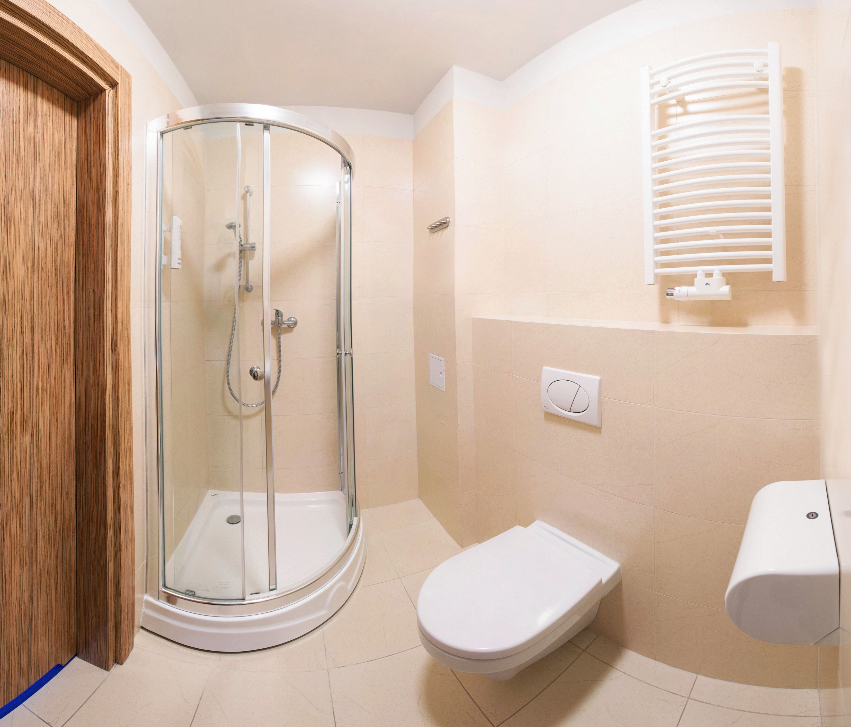 A bathroom with a glass-enclosed shower, a toilet, and a towel rack.