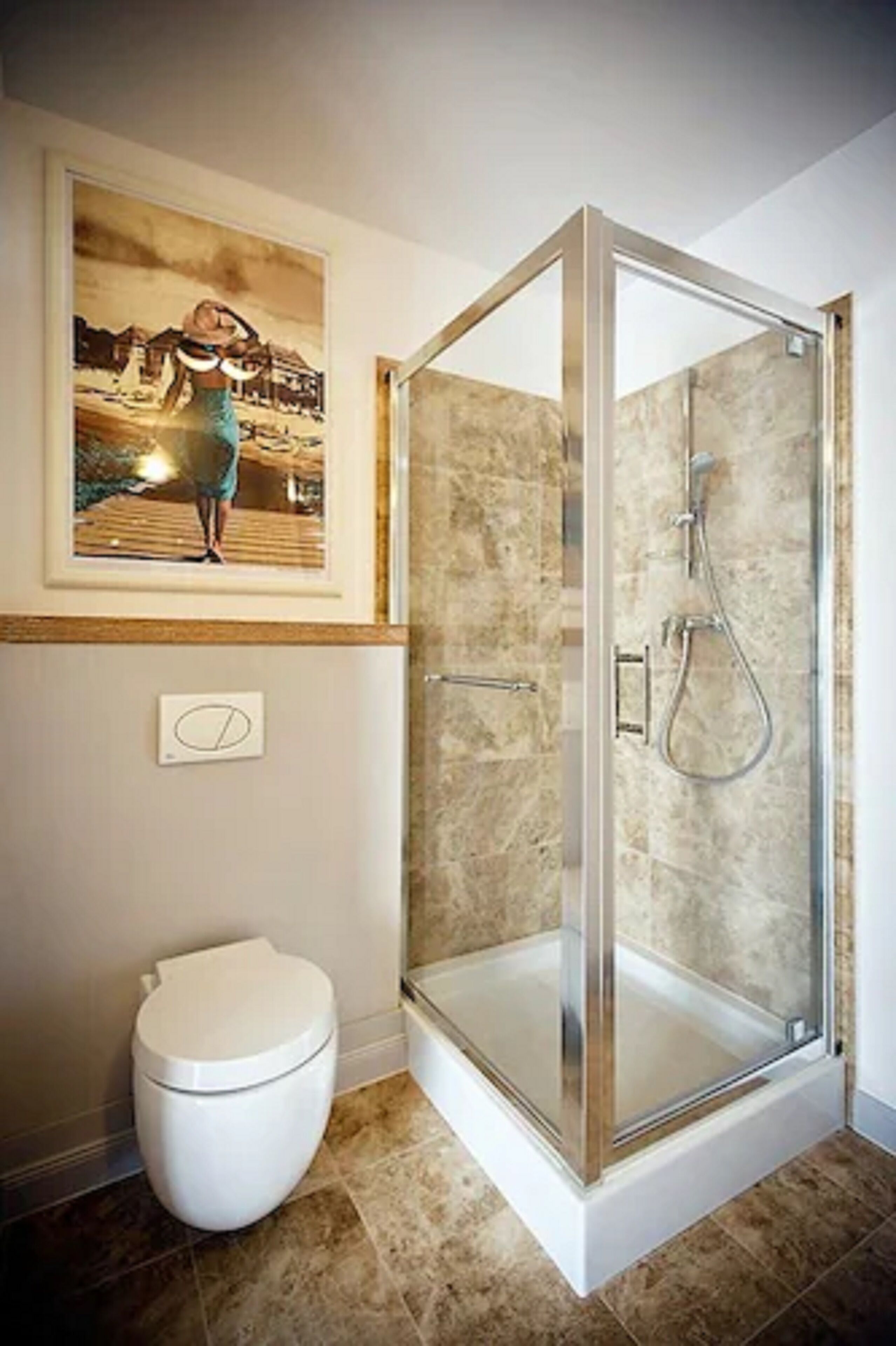 Een badkamer met een douchecabine van glas, een toilet en een inlijsting foto aan de muur.