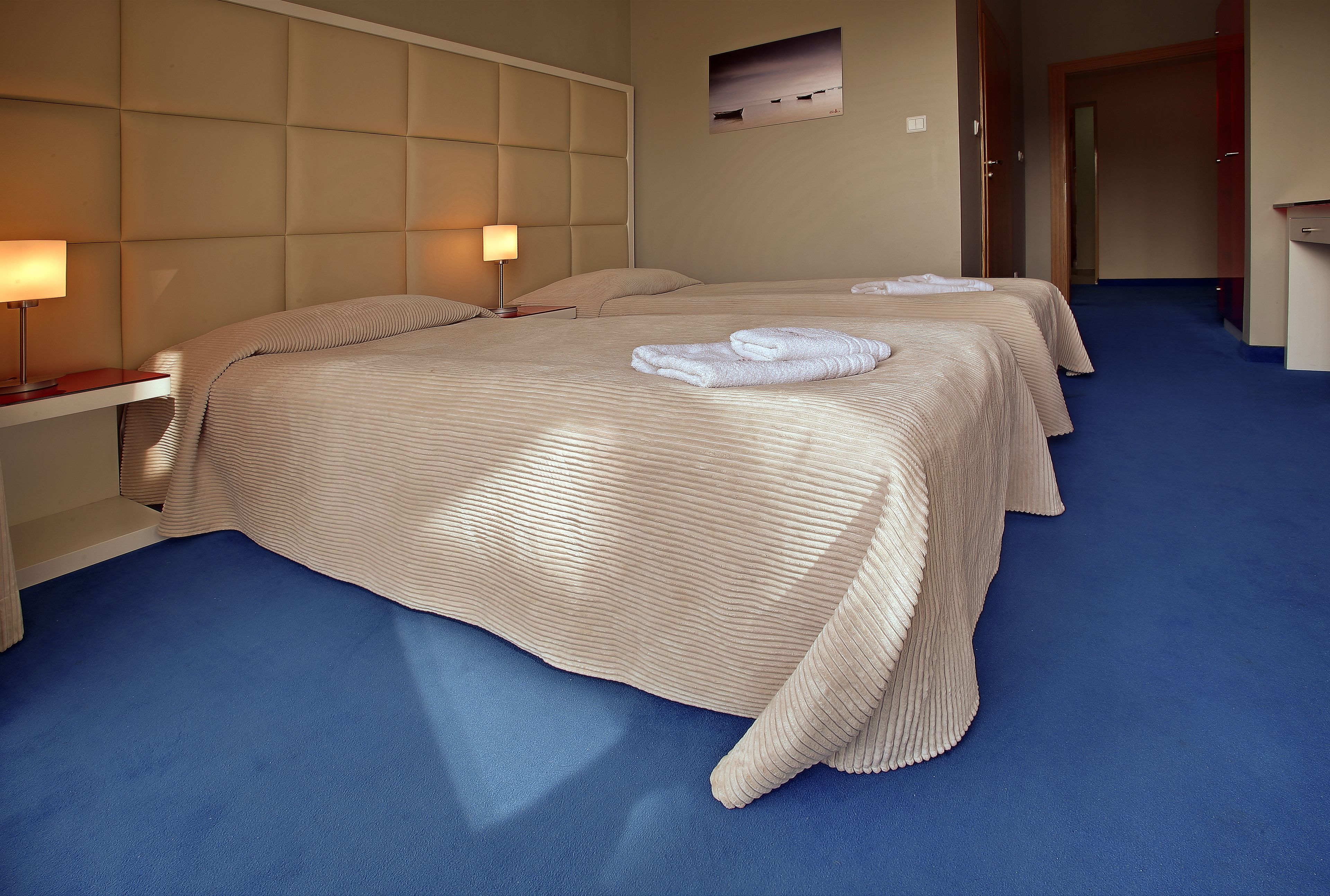 Une chambre d’hôtel avec un grand lit, une table de chevet, une lampe et un tableau au mur.