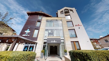 A multi-story hotel with a modern design, featuring a prominent entrance with glass doors and a sign for 'Villa Sentoza'.