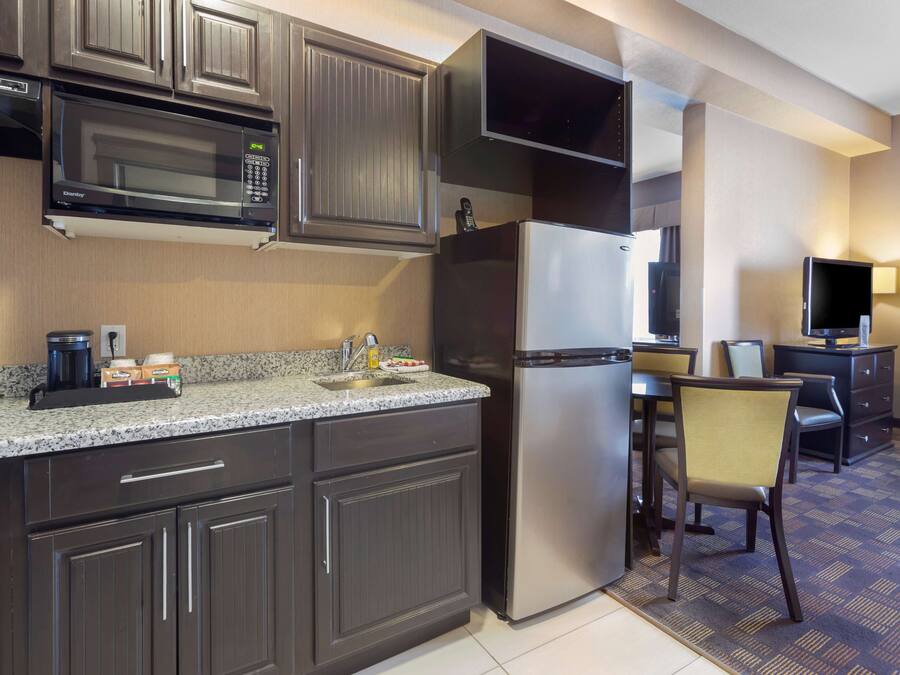 Cocina compacta con microondas, refrigerador y comedor con una silla y mesa.