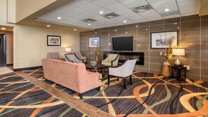 A hotel lobby with a seating area, a flat-screen TV, and a patterned carpet. - Best Western Plus Fox Creek (Fox Creek)