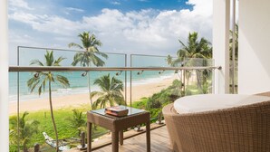A balcony with a view of the beach, a wicker sofa, and a small table with a book. - Shinagawa Beach (Balapitiya)