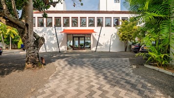 A building with a red awning, a paved entrance, and a clear sky.