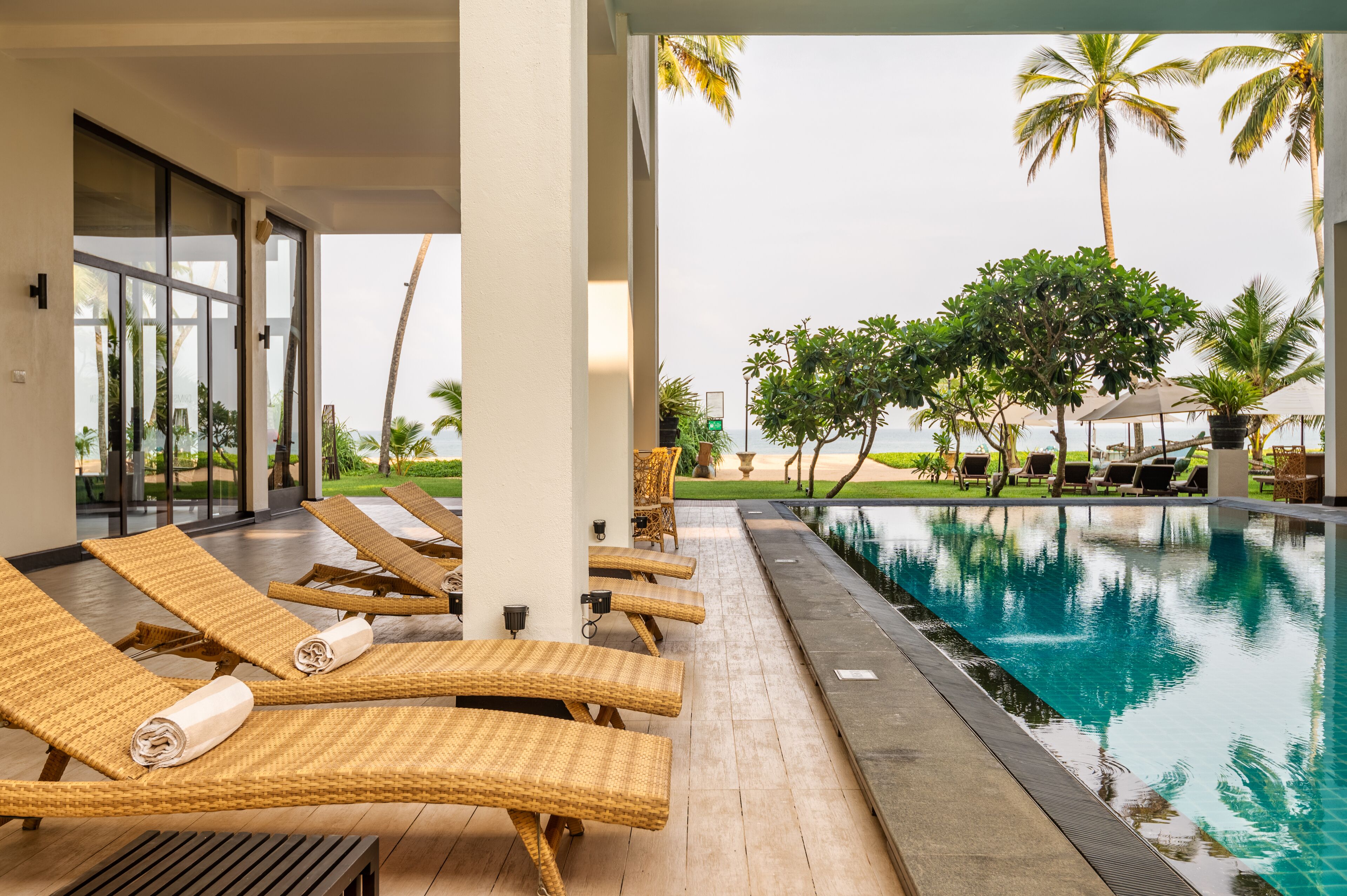Un espace aménagé au bord de la piscine, avec des chaises longues et une vue sur l’océan.