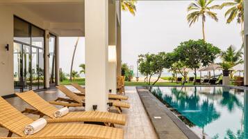 Un espace aménagé au bord de la piscine, avec des chaises longues et une vue sur l’océan.