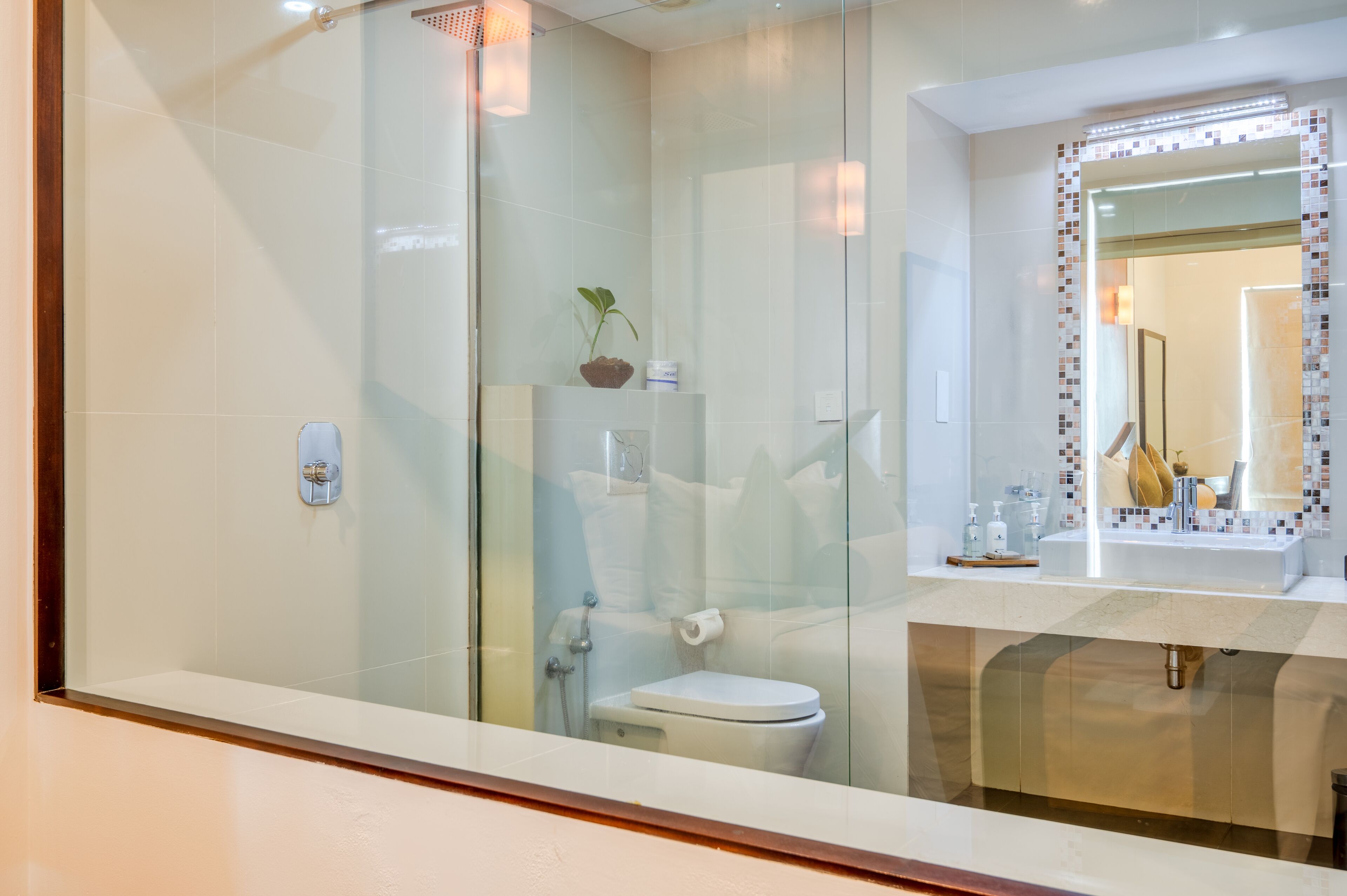 Un baño moderno con cabina de ducha de vidrio, inodoro y lavabo con espejo.