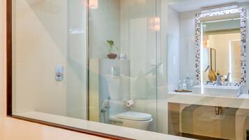 Un baño moderno con cabina de ducha de vidrio, inodoro y lavabo con espejo.