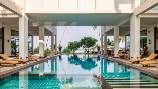 A swimming pool with lounge chairs and a view of the beach. - Shinagawa Beach (Balapitiya)