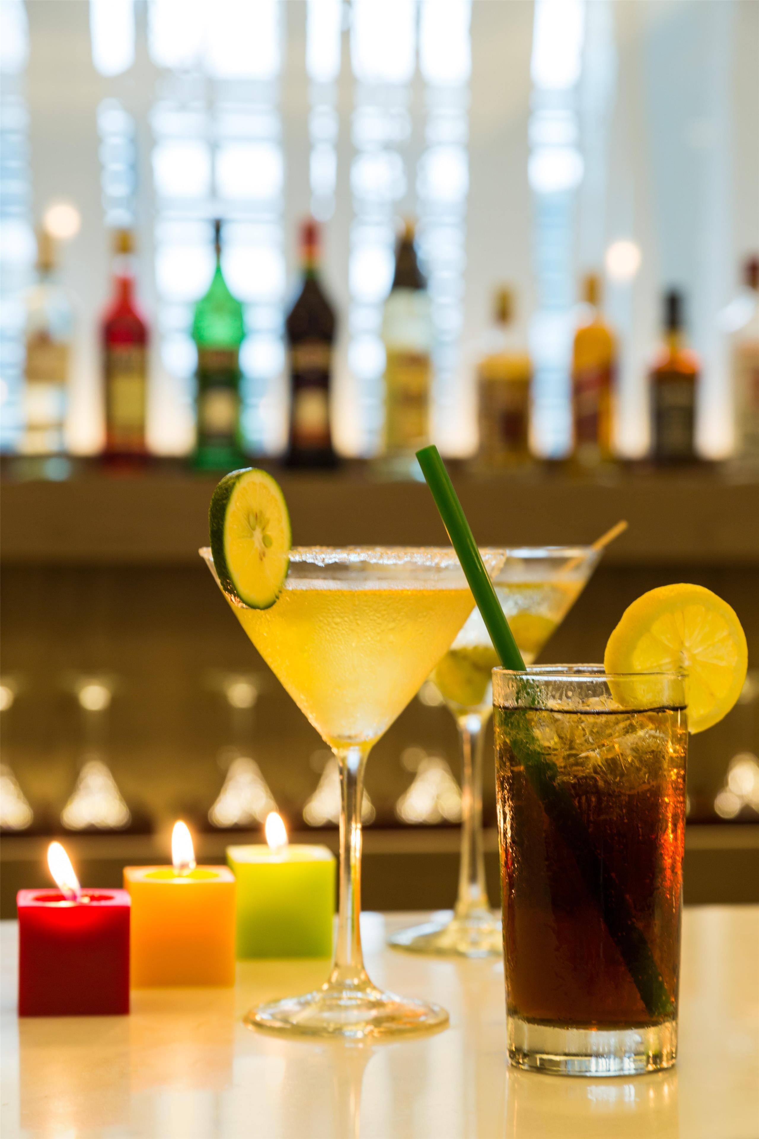 A bar setting with drinks, candles, and bottles in the background.