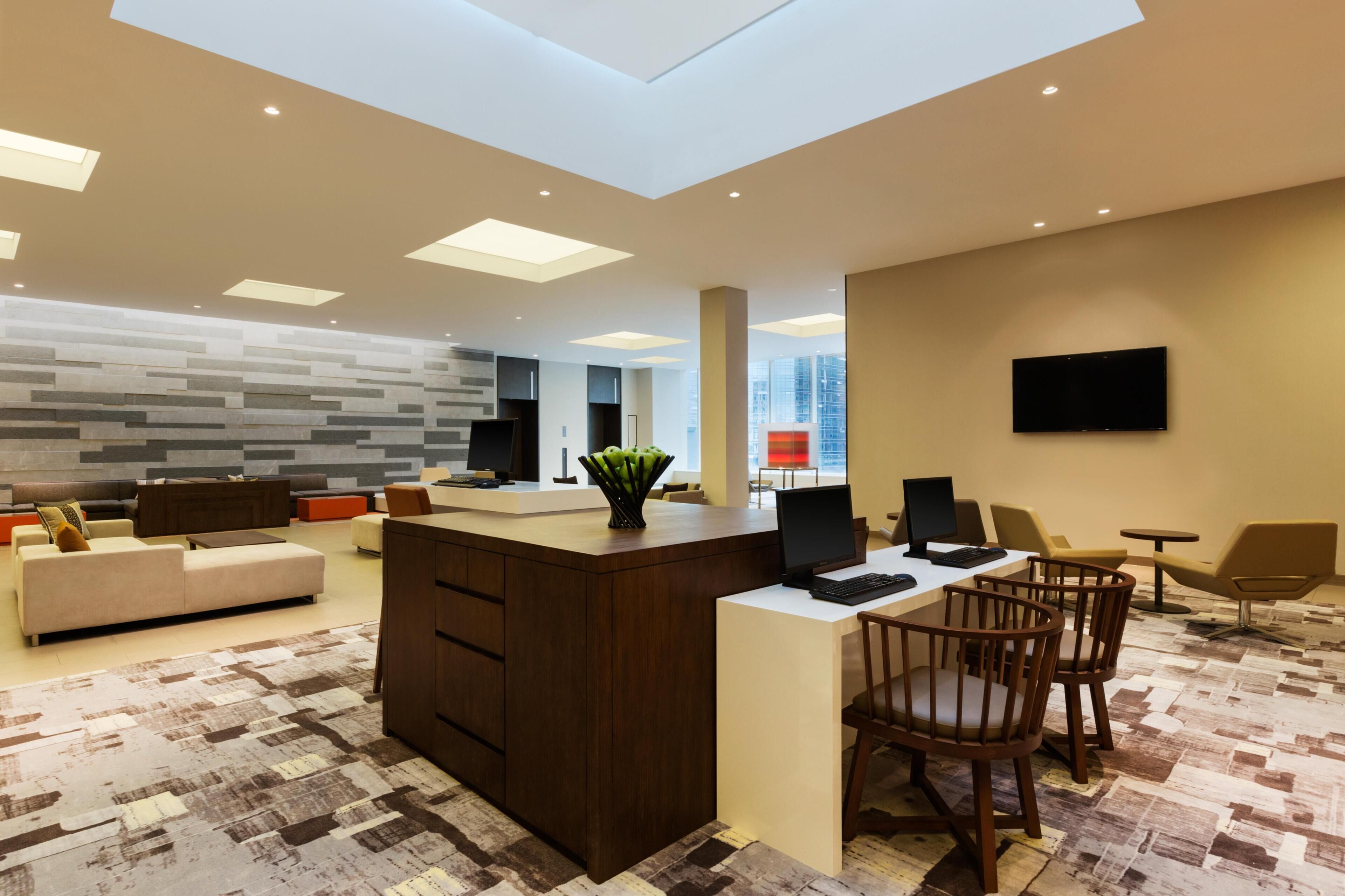 Un salon moderne avec un îlot central, un canapé, une table basse et un téléviseur fixé au mur.