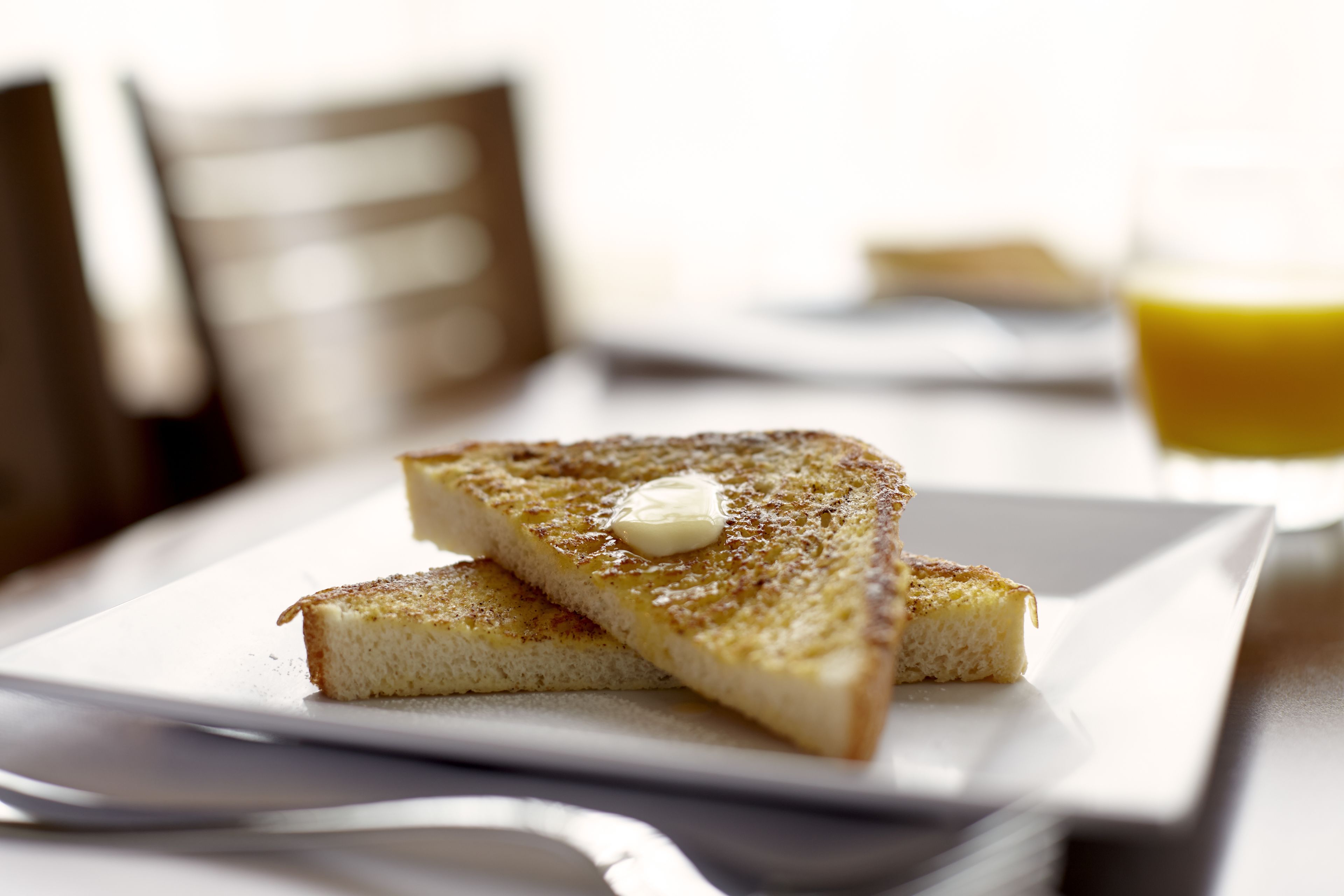 Uma fatia de pão torrado com manteiga sobre um prato branco.