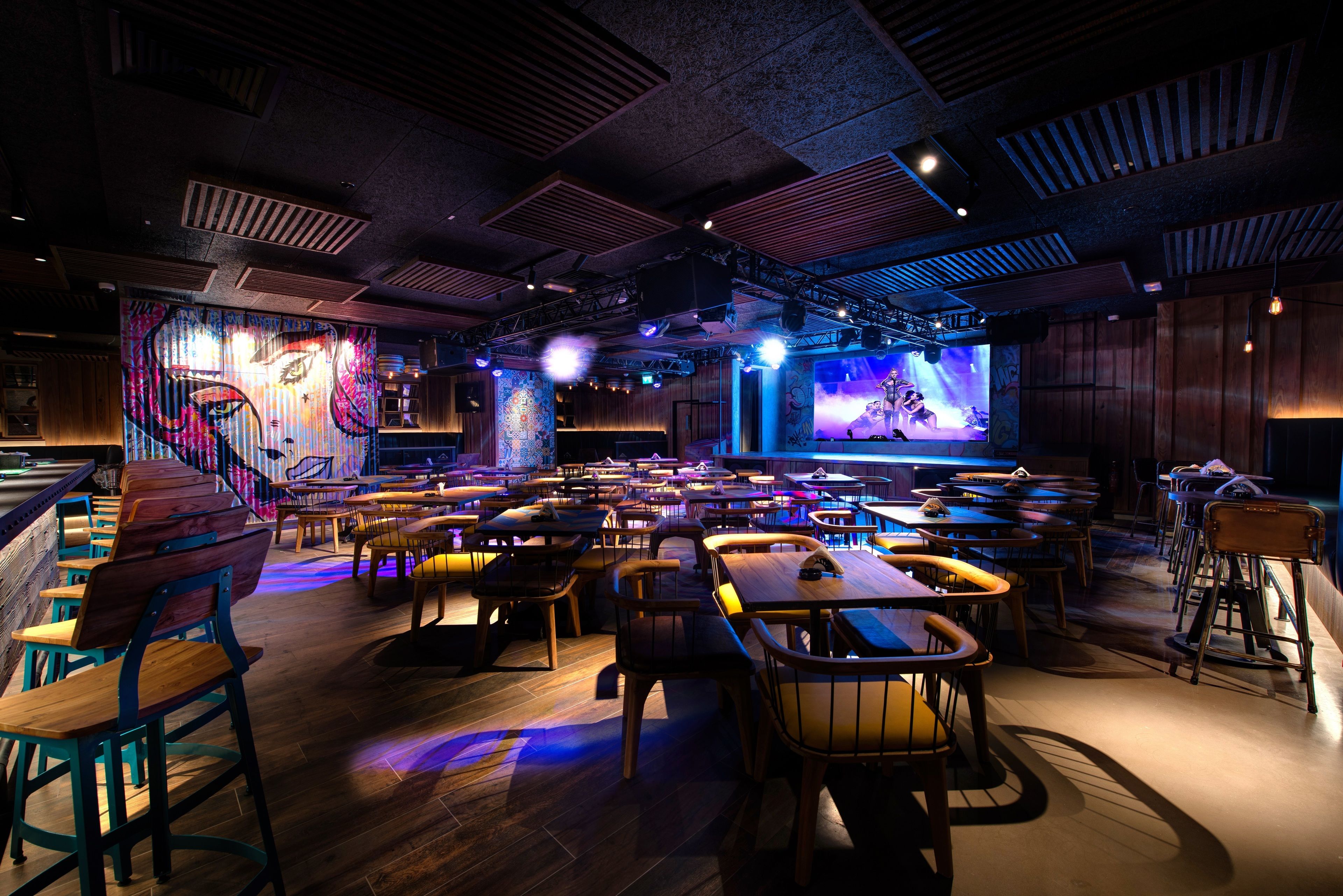 Amplia zona de bar con diversas opciones de asientos y un escenario para espectáculos.