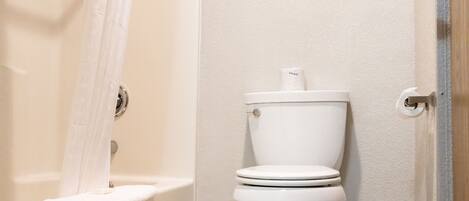 A bathroom with a toilet, a shower curtain, and a towel rack.