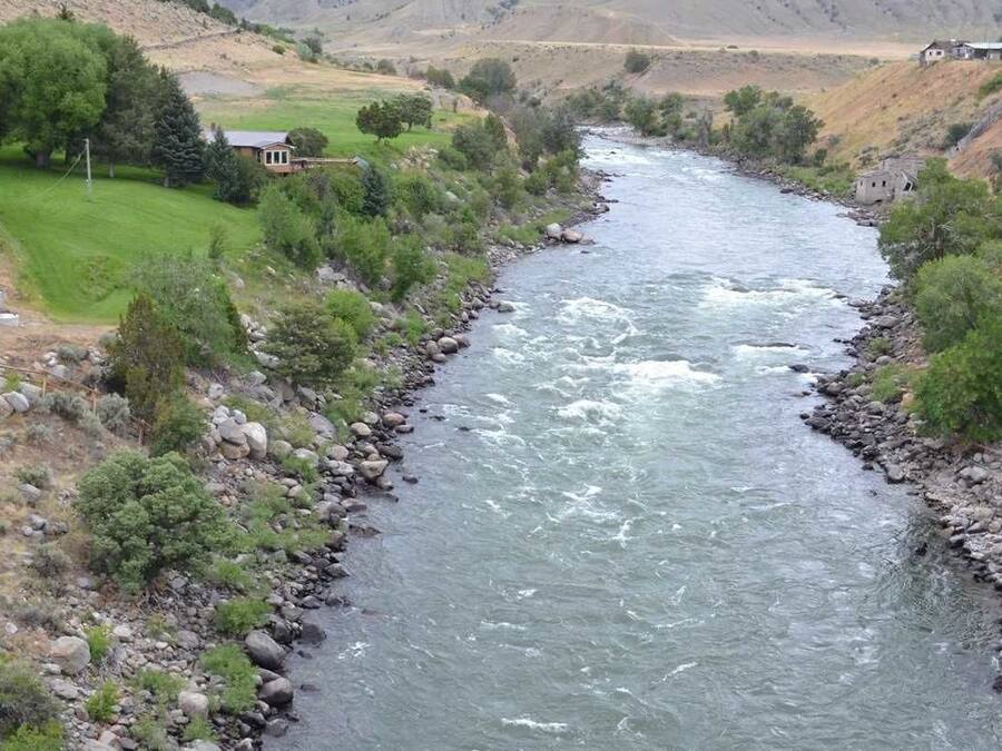 Un río que serpentea por un valle con casas a sus orillas.