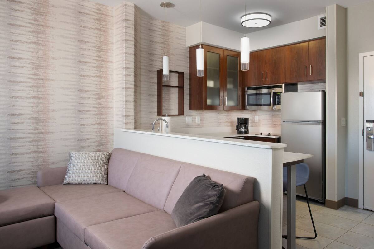 A modern kitchen with wooden cabinets, a stainless steel refrigerator, and a built-in microwave.